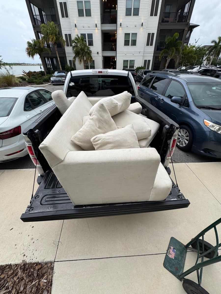 White sectional couch loaded in a pickup truck bed